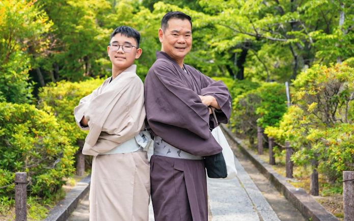 Men wearing traditional kimonos in a Kyoto garden pathway.