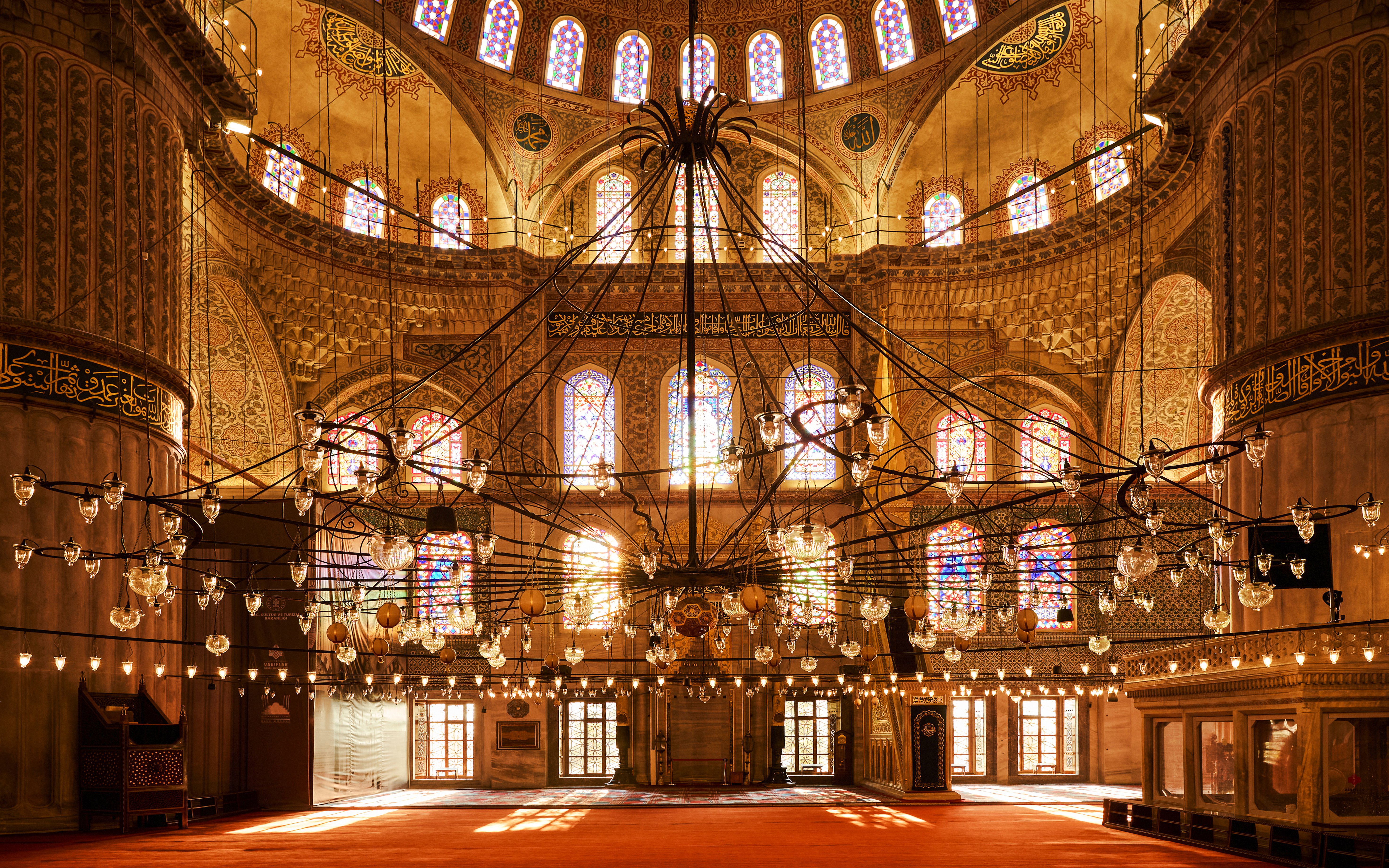 Prayer hall interior with chandeliers and stained glass windows, Blue Mosque, Istanbul.