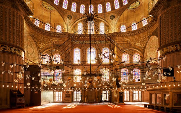 Prayer hall interior with chandeliers and stained glass windows, Blue Mosque, Istanbul.