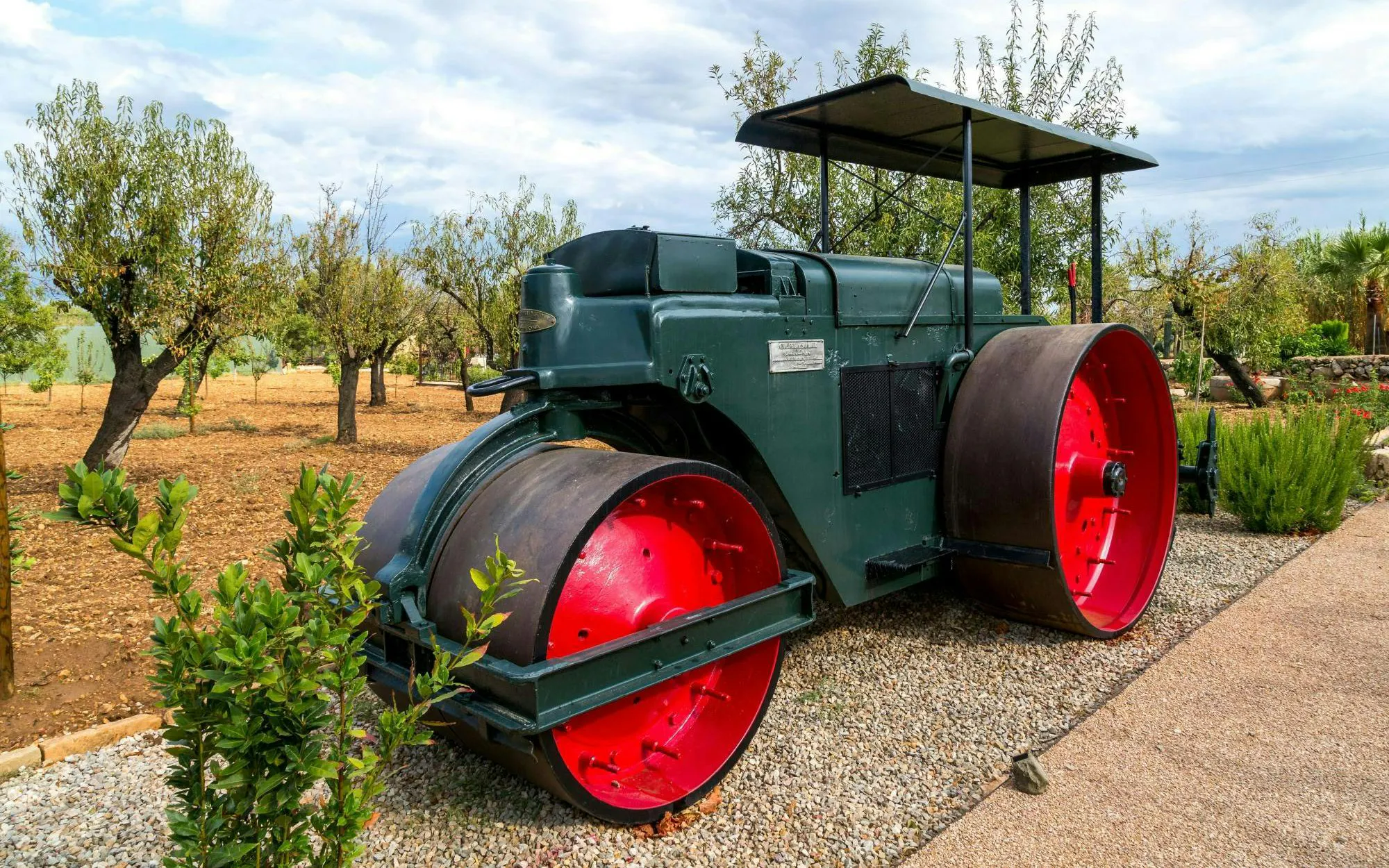 Roller at a Majorca winery estate surrounded by trees and gravel path.