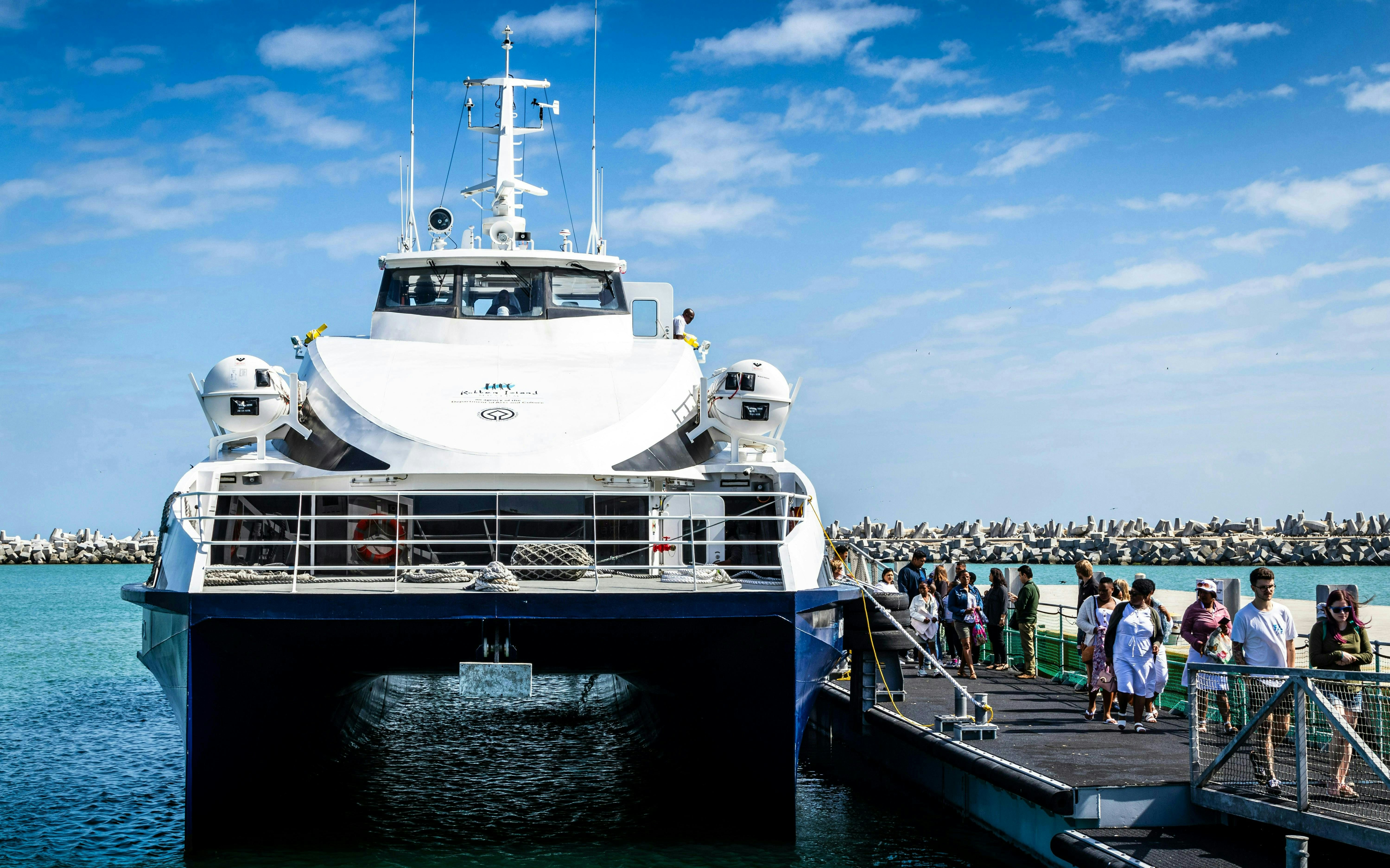 Ferry docked at Robben Island pier with passengers boarding for a prison tour.