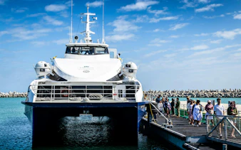 Ferry docked at Robben Island pier with passengers boarding for a prison tour.