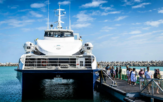 Ferry docked at Robben Island pier with passengers boarding for a prison tour.