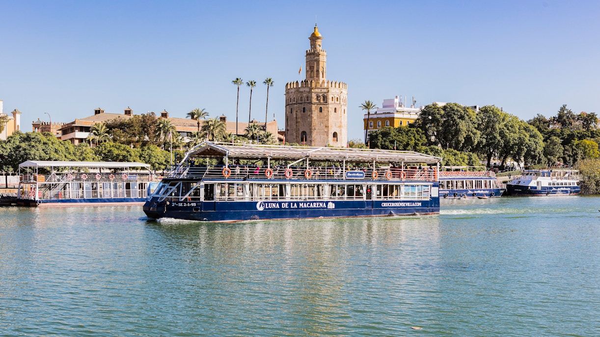 Cruise boat on Guadalquivir River passing Torre del Oro in Seville.