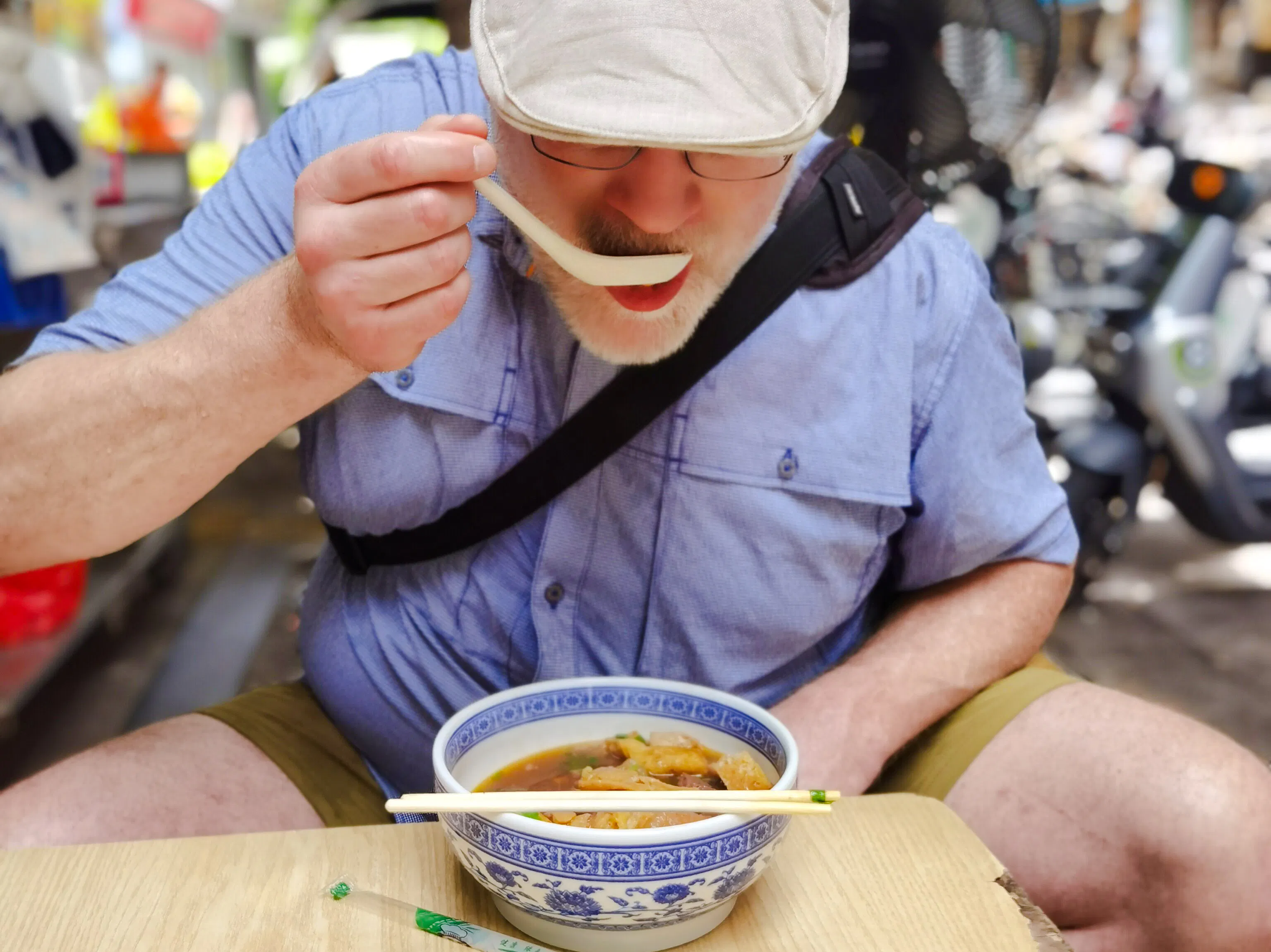 Man enjoying local noodle soup in Shenzhen street market.