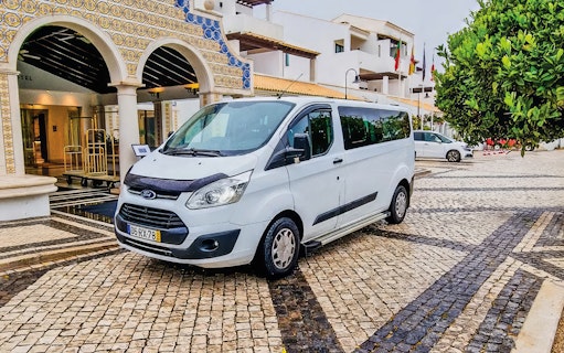 Minibus for private Faro airport transfers parked outside a hotel entrance.