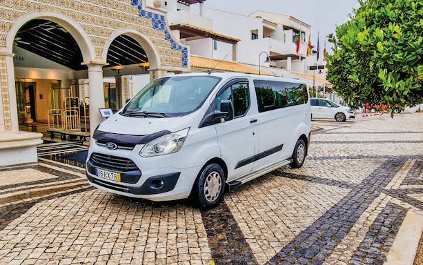 Minibus for private Faro airport transfers parked outside a hotel entrance.