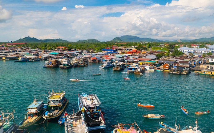 Boats docked at Semporna waterfront with colorful buildings, near Tawau Airport transfers.