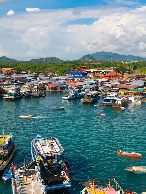 Boats docked at Semporna waterfront with colorful buildings, near Tawau Airport transfers.
