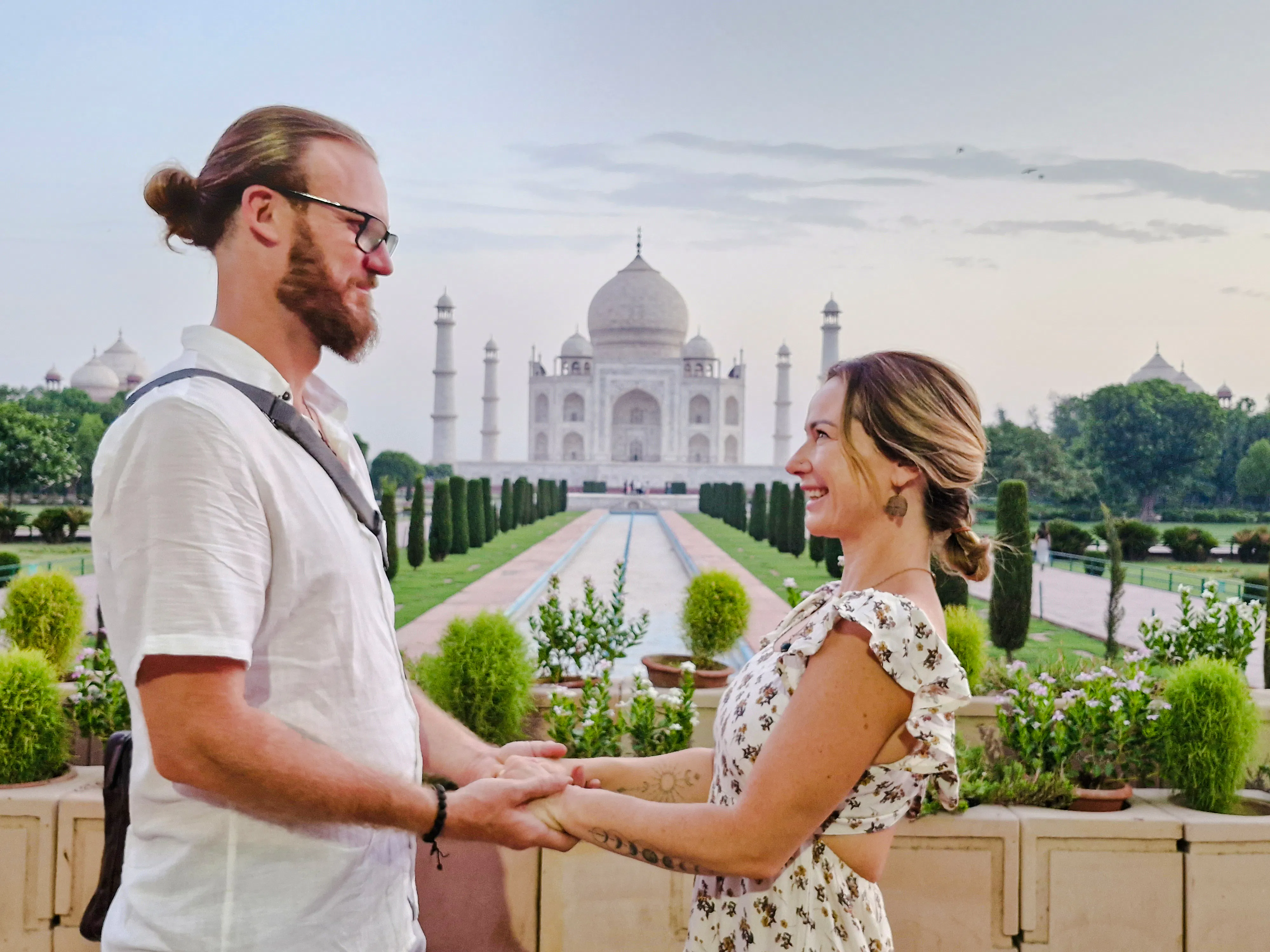 Couple holding hands with the Taj Mahal in the background at sunrise, Agra.