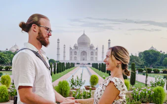 Couple holding hands with the Taj Mahal in the background at sunrise, Agra.
