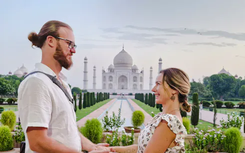 Couple holding hands with the Taj Mahal in the background at sunrise, Agra.