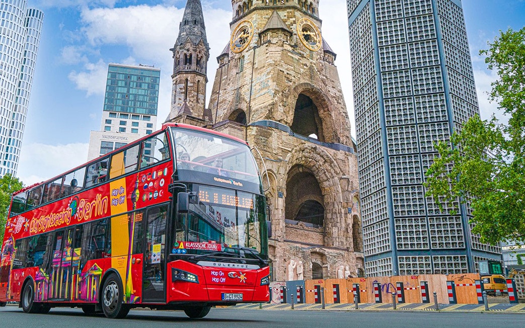 Red double-decker bus on Berlin Hop On & Hop Off tour near Kaiser Wilhelm Memorial Church.