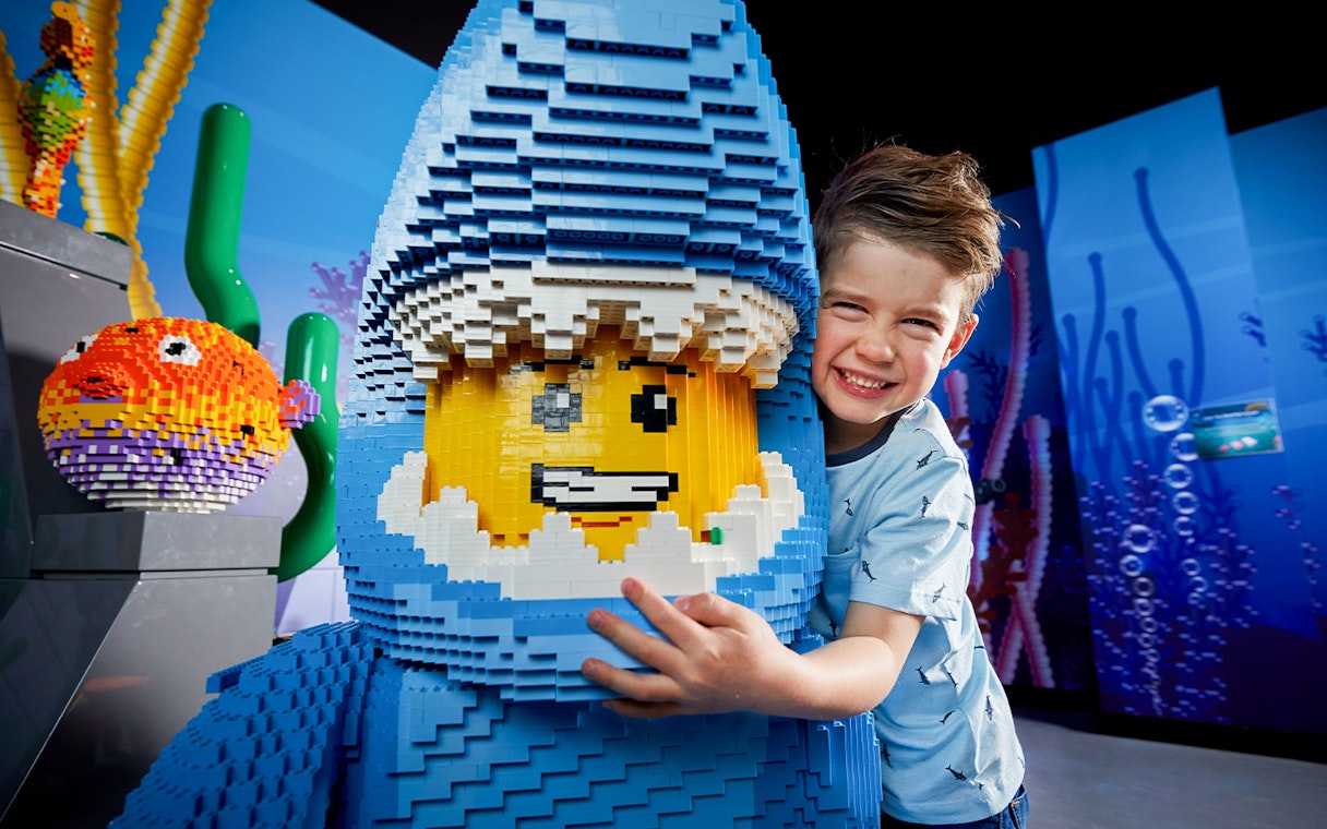 Child hugging LEGO shark figure at LEGOLAND Discovery Centre.