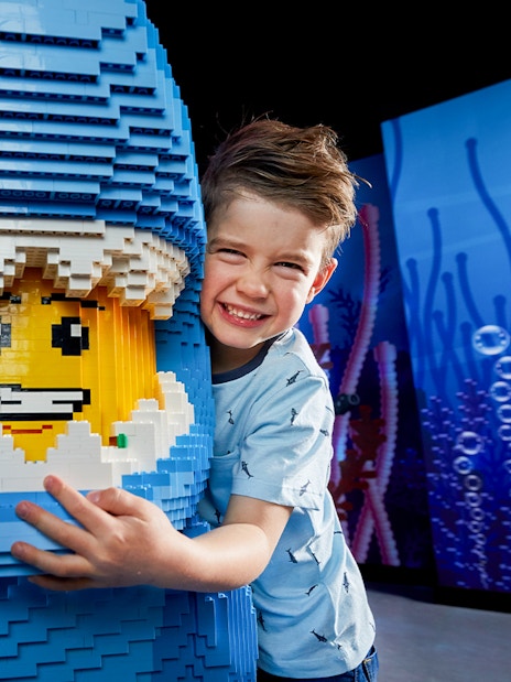 Child hugging LEGO shark figure at LEGOLAND Discovery Centre.