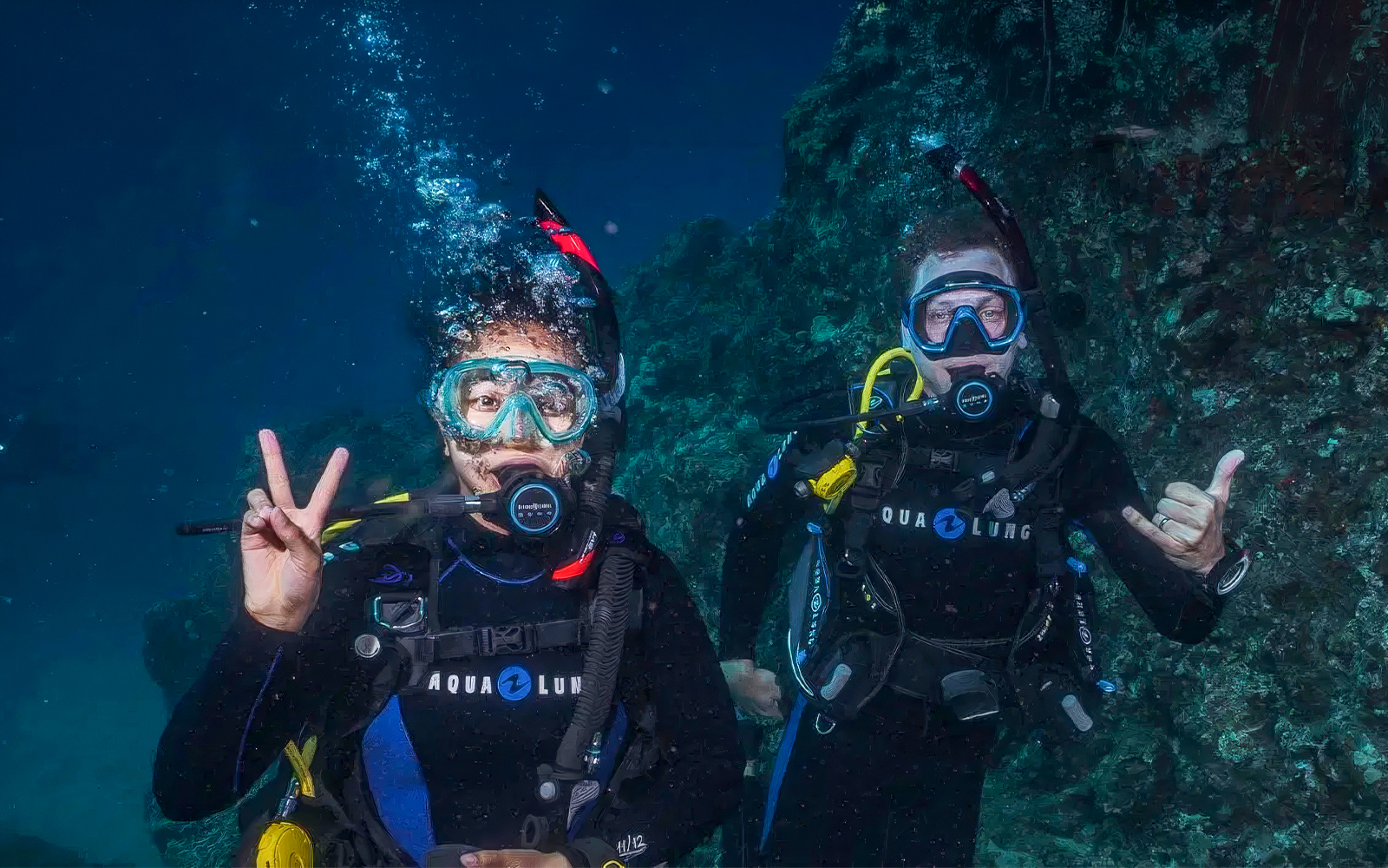 Beginners scuba diving in Maui, two divers underwater near coral reef.