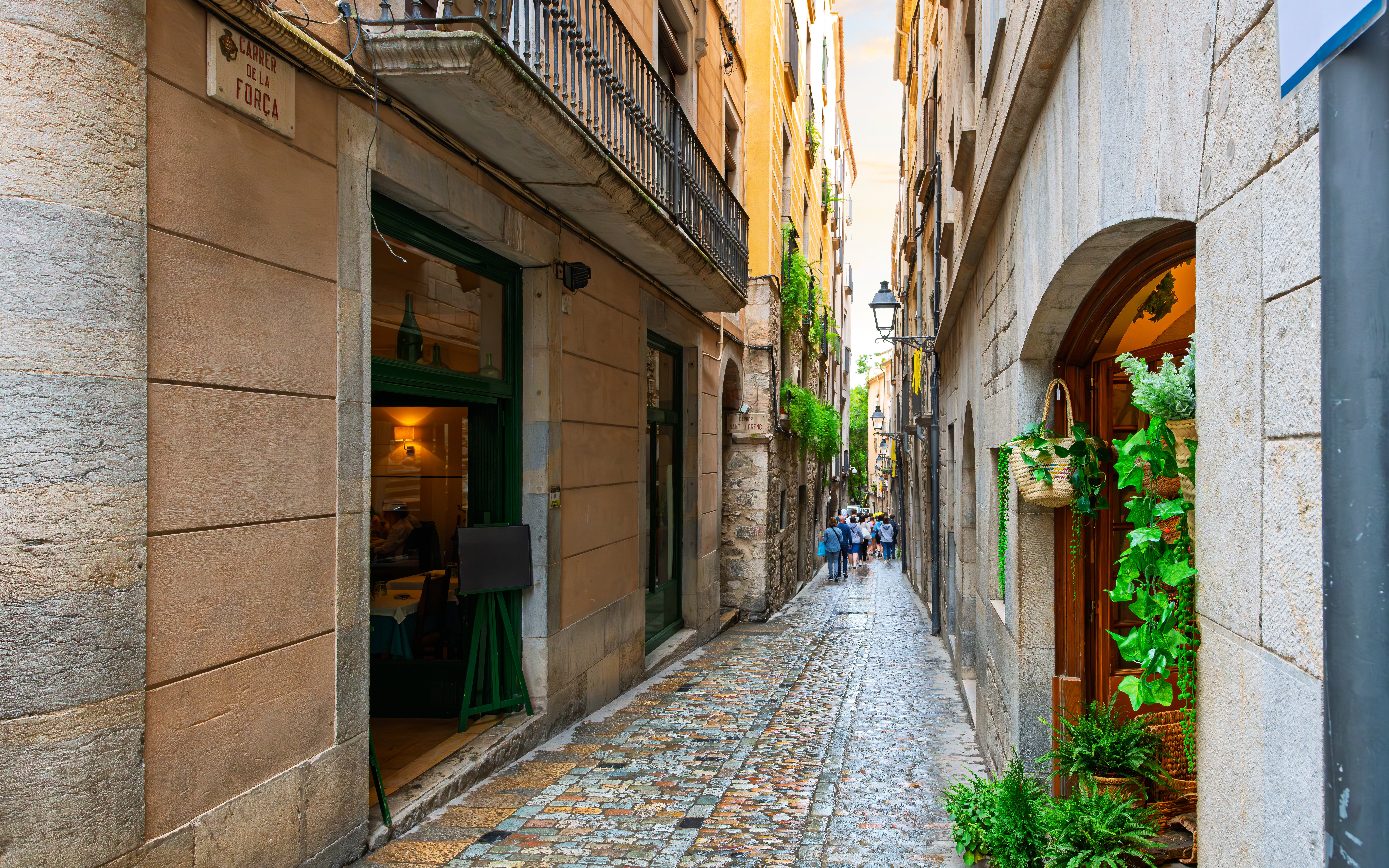 Calle de la Forca in El Call Jewish Quarter, Girona, Spain, with cobblestone street and historic buildings.