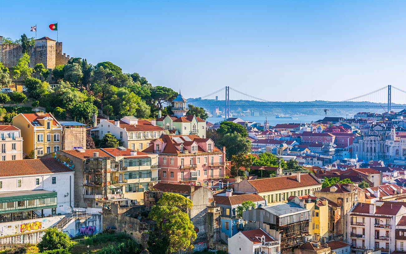 Lisbon cityscape from Church of Graça terrace, featuring São Jorge Castle and 25 de Abril Bridge.