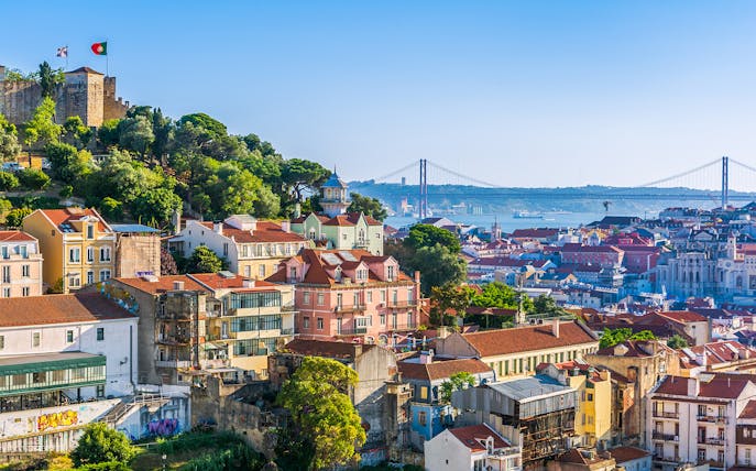 Lisbon cityscape from Church of Graça terrace, featuring São Jorge Castle and 25 de Abril Bridge.