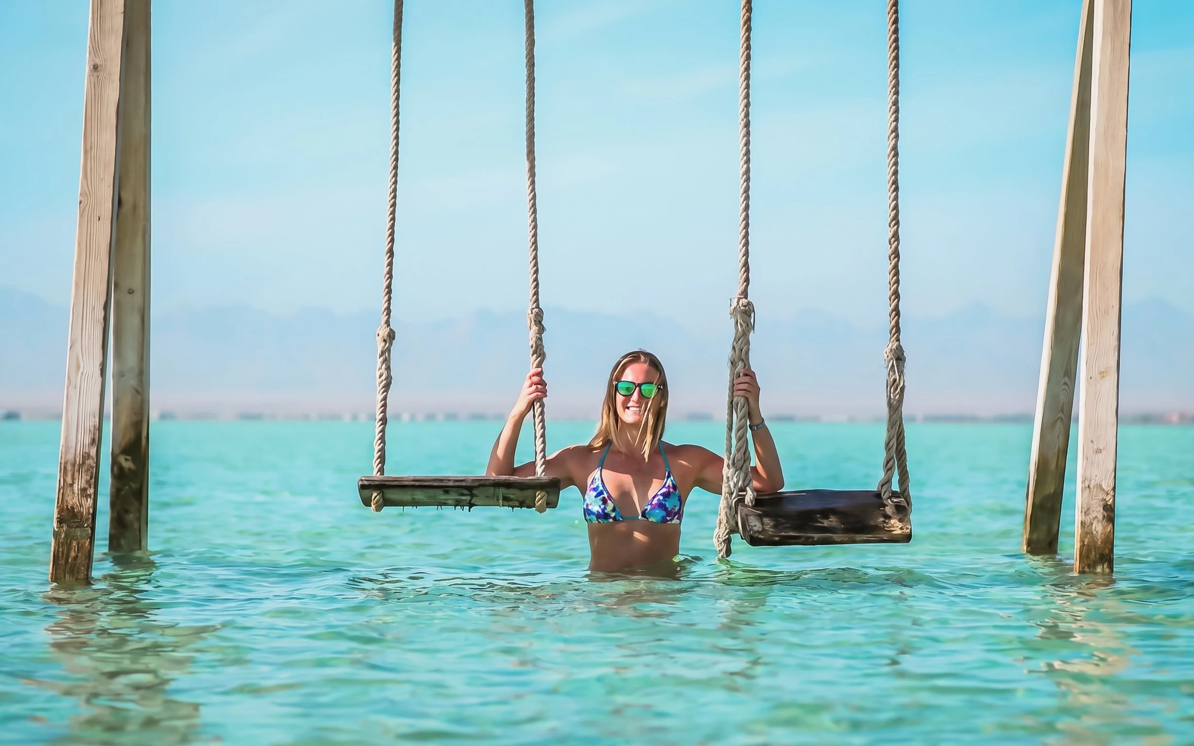 Person enjoying swings in clear water at Orange Bay, Giftun Island, Hurghada.