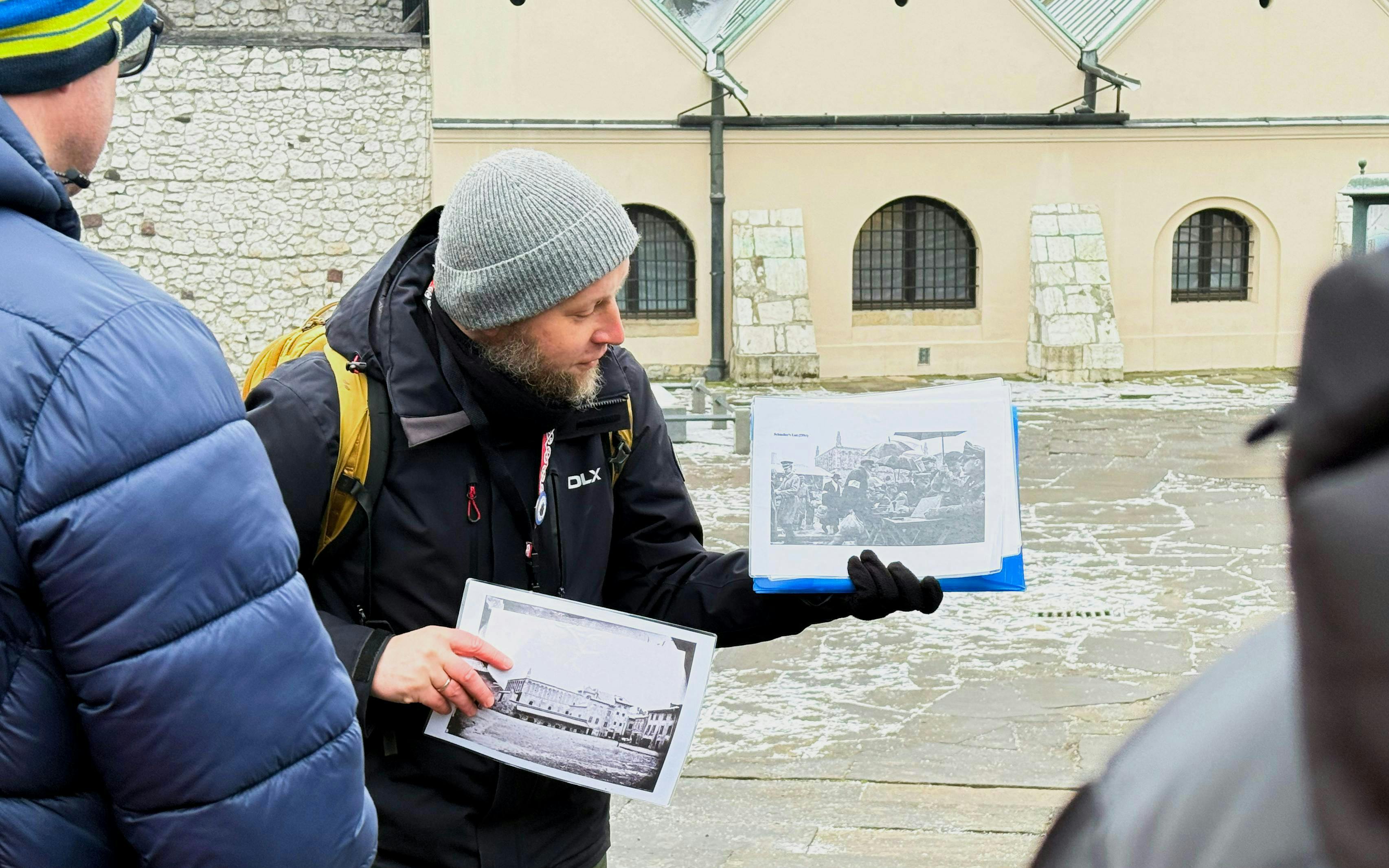 Guide showing historical photos during Krakow Schindler’s Story tour in Kazimierz district.
