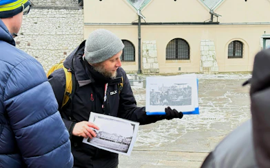 Guide showing historical photos during Krakow Schindler’s Story tour in Kazimierz district.