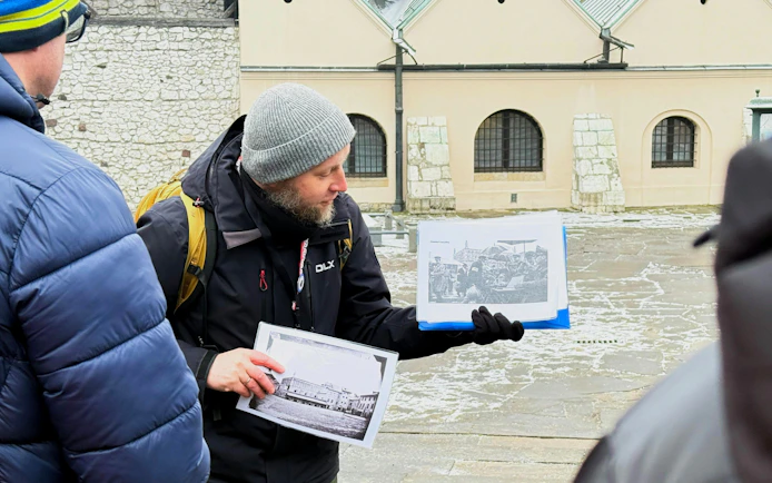 Guide showing historical photos during Krakow Schindler’s Story tour in Kazimierz district.