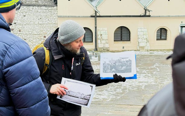 Guide showing historical photos during Krakow Schindler’s Story tour in Kazimierz district.