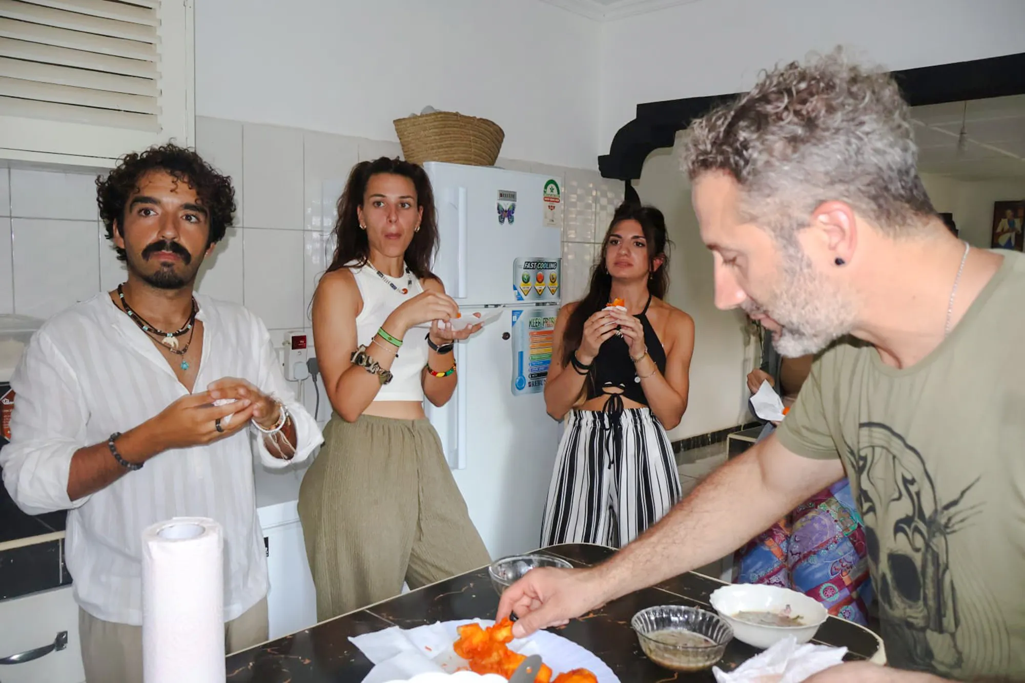 Cooking class participants preparing food with a local in Diani Beach kitchen.