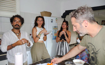 Cooking class participants preparing food with a local in Diani Beach kitchen.