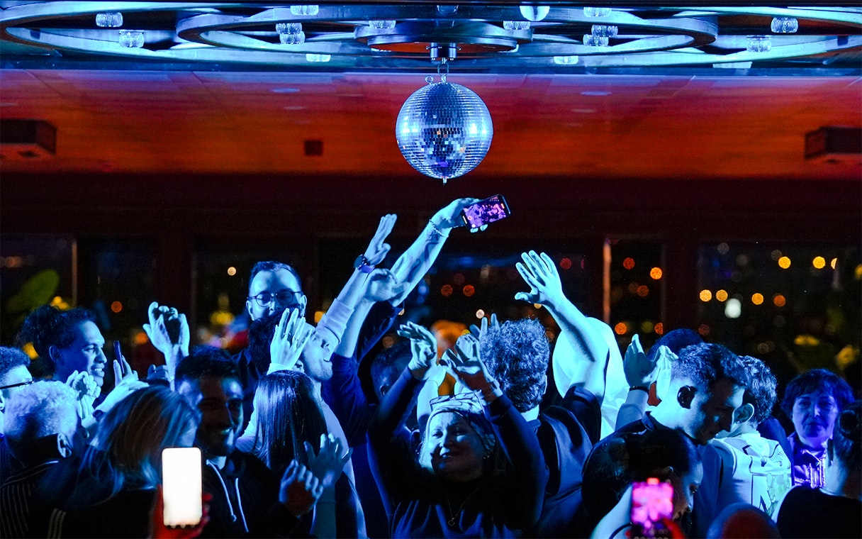 Passengers dancing under disco ball on Bosphorus dinner cruise with live DJ.