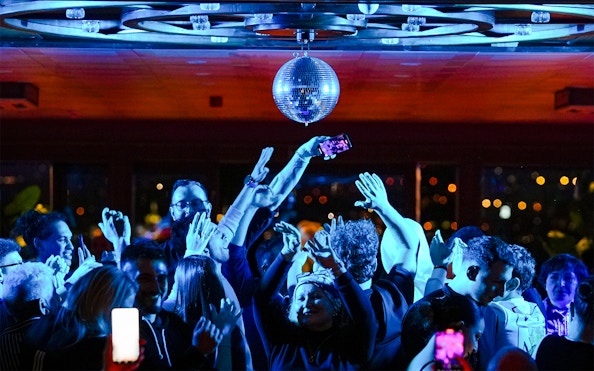 Passengers dancing under disco ball on Bosphorus dinner cruise with live DJ.