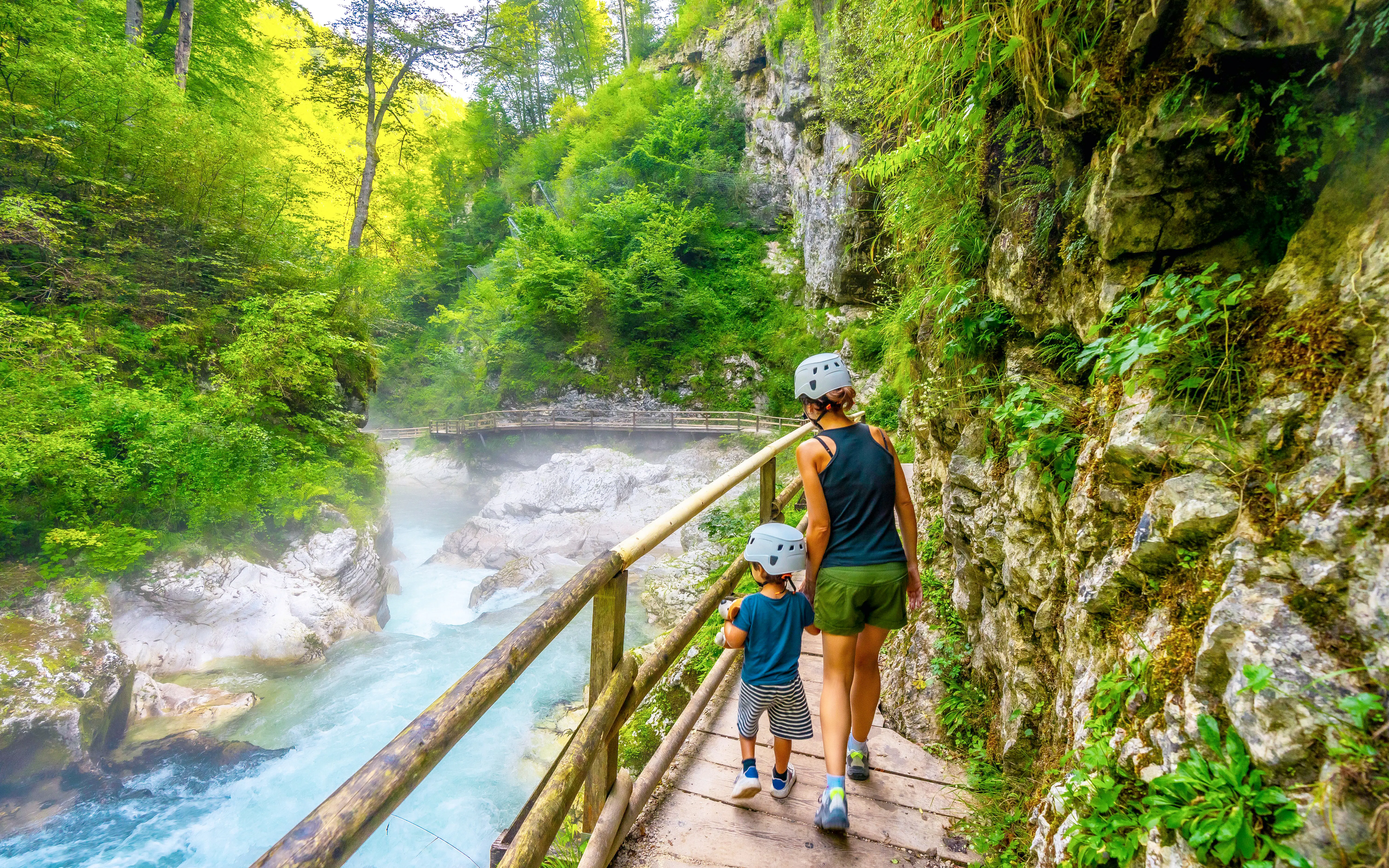 Mother and son hiking along a wooden path in Vintgar Gorge, Slovenia.