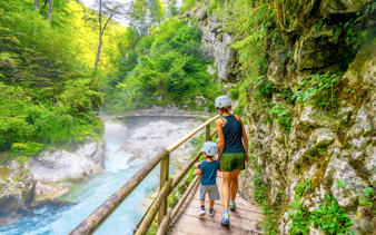 Mother and son hiking along a wooden path in Vintgar Gorge, Slovenia.