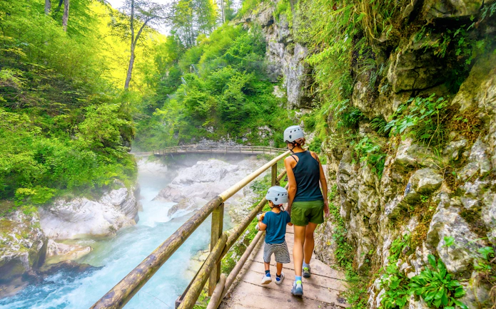 Mother and son hiking along a wooden path in Vintgar Gorge, Slovenia.