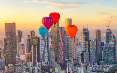 Hot air balloons over Melbourne skyline at sunrise.