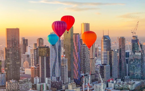 Hot air balloons over Melbourne skyline at sunrise.