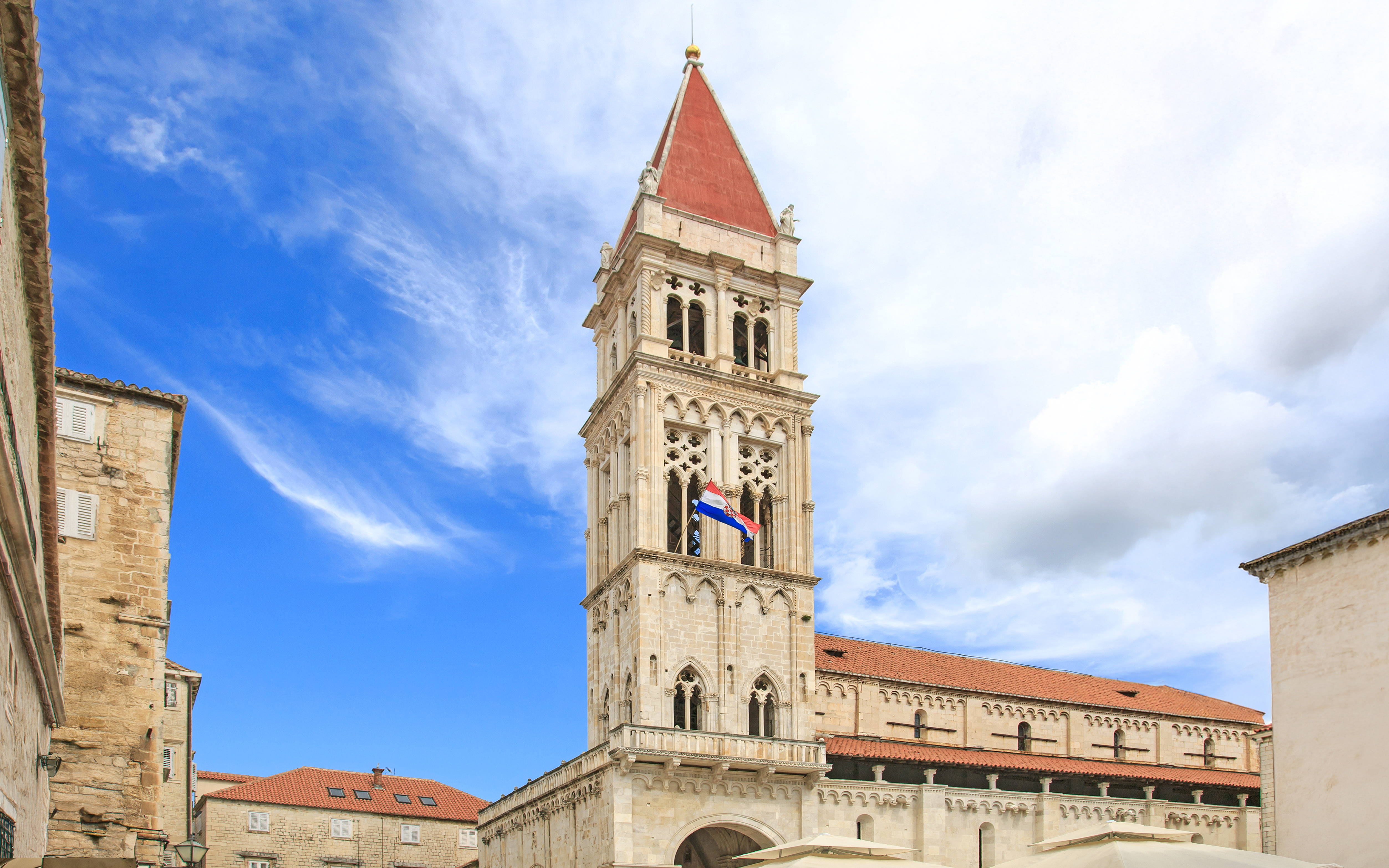 Cathedral of St. Lawrence bell tower in Trogir, Croatia against a blue sky.