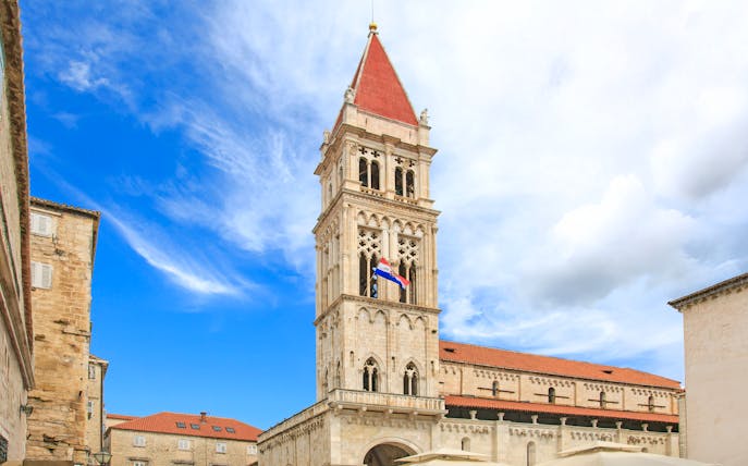 Cathedral of St. Lawrence bell tower in Trogir, Croatia against a blue sky.