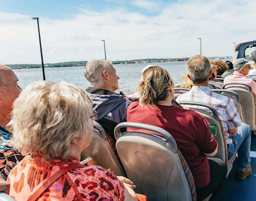Tourists enjoying the City Sightseeing 1-Day Hop-On Hop-Off Bus Tour in New Orleans, passing by iconic landmarks