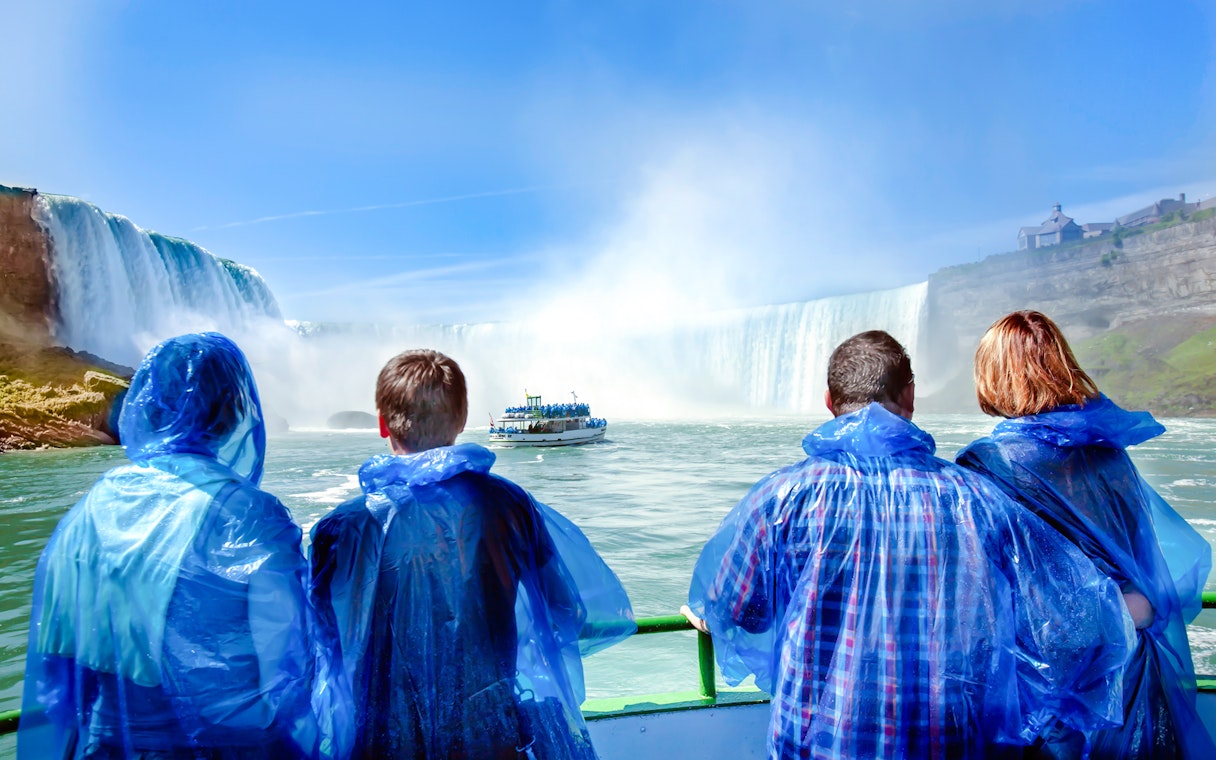 Tourists in blue ponchos view Niagara Falls from a boat.