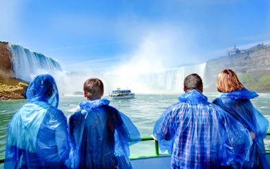 Tourists in blue ponchos view Niagara Falls from a boat.