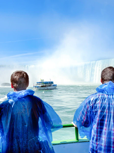 Tourists in blue ponchos view Niagara Falls from a boat.