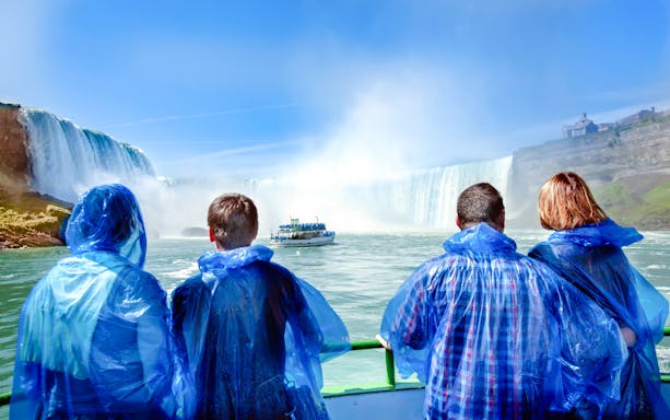 Tourists in blue ponchos view Niagara Falls from a boat.