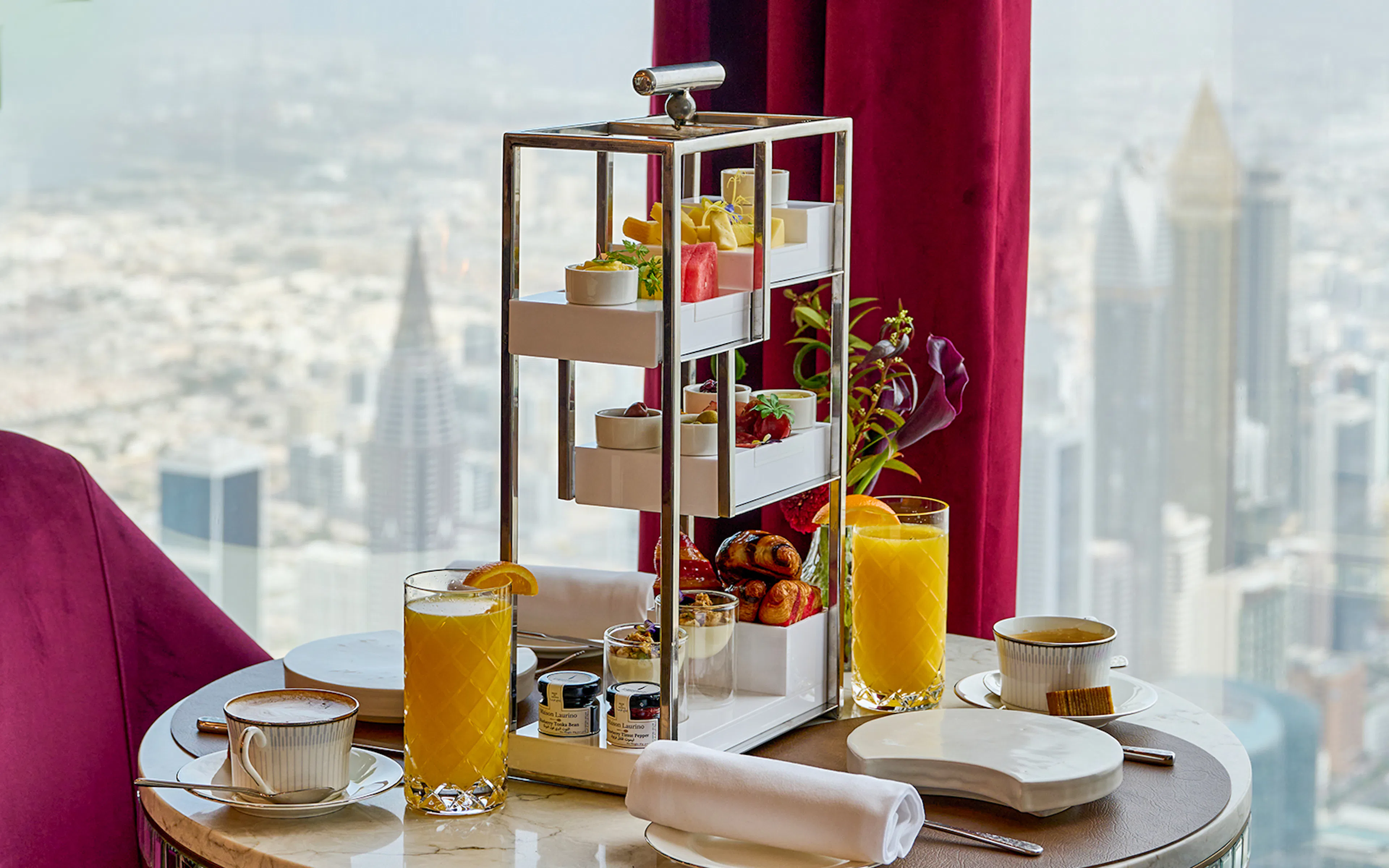 High tea setup with pastries and drinks at At.Mosphere, Burj Khalifa, overlooking Dubai.