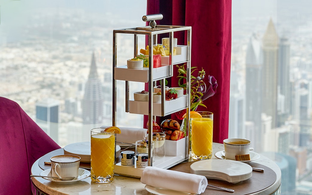 High tea setup with pastries and drinks at At.Mosphere, Burj Khalifa, overlooking Dubai.