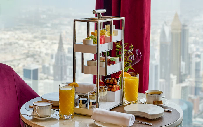 High tea setup with pastries and drinks at At.Mosphere, Burj Khalifa, overlooking Dubai.