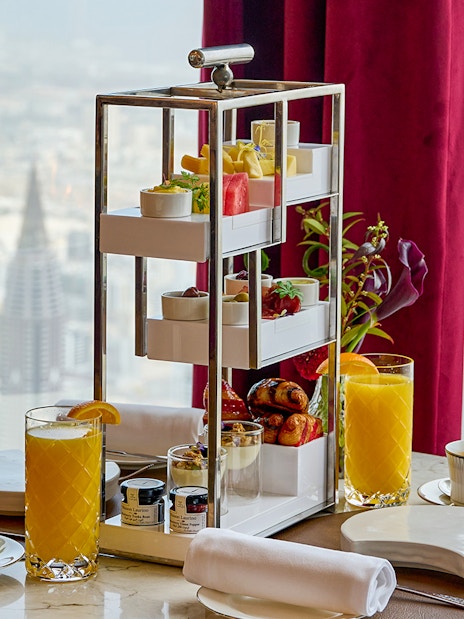 High tea setup with pastries and drinks at At.Mosphere, Burj Khalifa, overlooking Dubai.