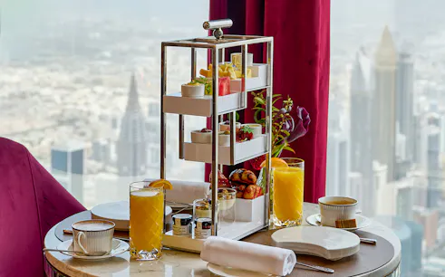 High tea setup with pastries and drinks at At.Mosphere, Burj Khalifa, overlooking Dubai.