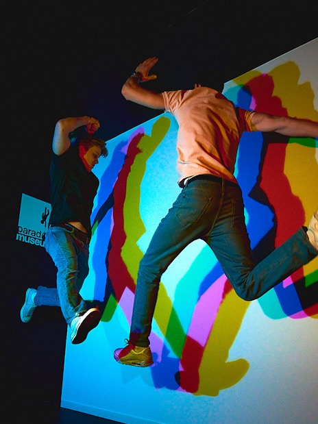 Visitors jumping in front of colorful shadow display at Paradox Museum.